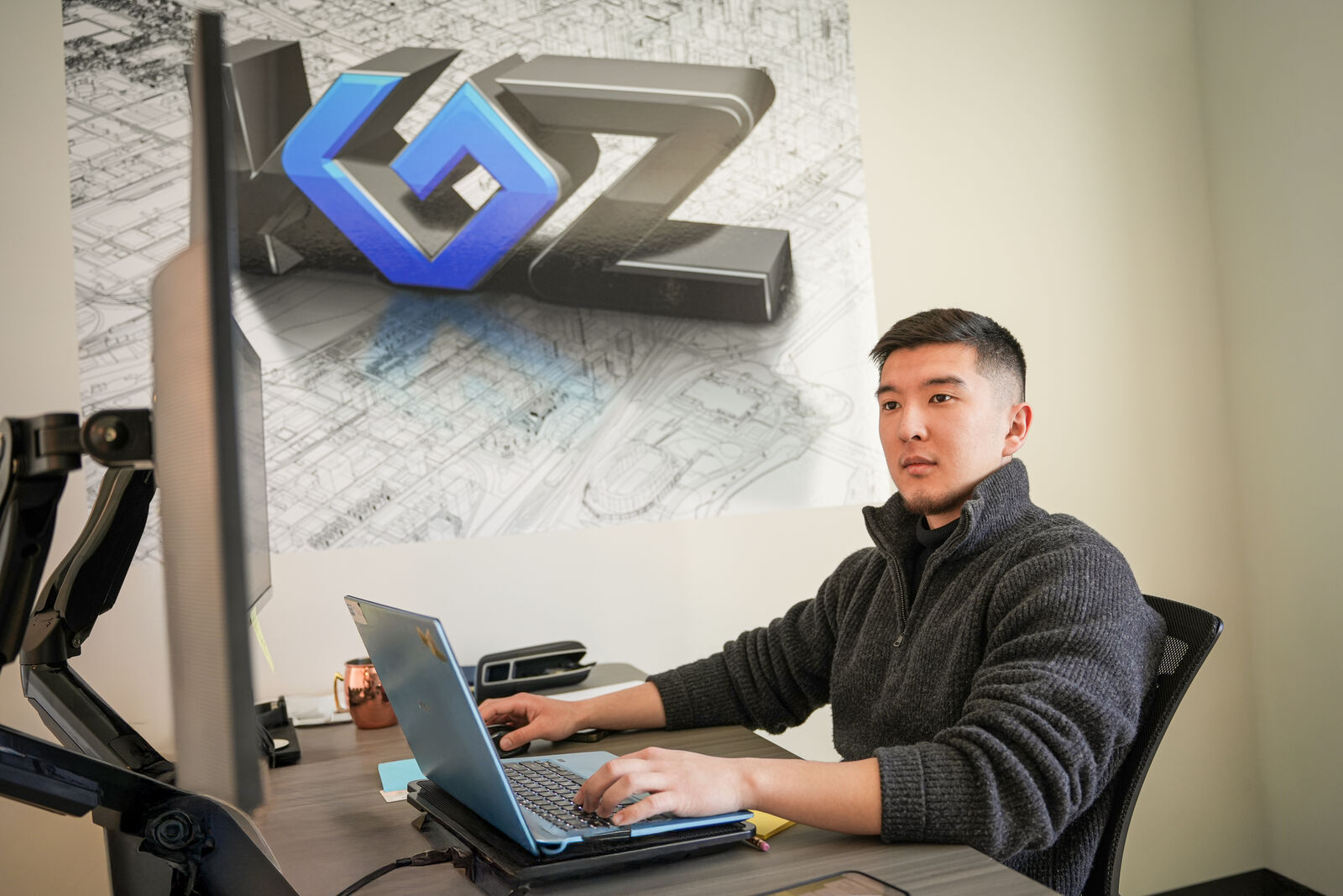 KGZ Transport team member working at a laptop with large KGZ logo wall art in the background